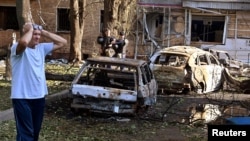 A man stands next to burnt-out cars in the courtyard of a multi-story residential building, which according to local authorities was hit by debris from a destroyed Ukrainian missile, in Kursk, Russia Aug. 11, 2024.