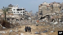 Palestinians walk past a building destroyed in the Israeli bombardment of the Gaza Strip in Gaza City, Jan. 3, 2024.