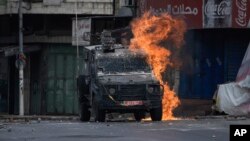 A Molotov cocktail thrown by a Palestinian protester explodes on an Israeli armored vehicle during clashes with Israeli security forces following a military raid in the West Bank city of Nablus, July 7, 2023.