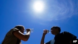 FILE - Tony Berastegui Jr. and his sister Giselle Berastegui drink water, July 17, 2023, in Phoenix. 