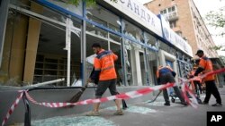 Workers sweep up broken glass at a damaged building after a reported drone attack in Moscow, July 24, 2023.