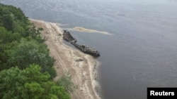 A view shows an old barge on a dried-up river bank after a water level in Dnipro River sharply dropped, after Kakhovka dam destruction, amid Russia's attack on Ukraine, near Zaporizhzhia, Ukraine, June 11, 2023. 
