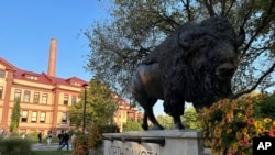 FILE - Students walk near Minard Hall and a bison statue on the campus of North Dakota State University on Sept. 20, 2023, in Fargo, N.D. 