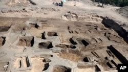 Archaeologists observe the site where they discovered 63 mud-brick tombs at the Tell al-Deir necropolis, in the Nile Delta town of Damietta, about 125 miles (200 km) north of Cairo, Egypt. (Egypt's Supreme Council of Antiquities via AP)