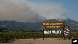 FILE - Smoke billows from a fire burning in the mountains over Napa Valley, Oct. 13, 2017, in Oakville, Calif.
