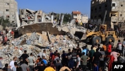 Palestinian rescuers look for survivors as others watch a digger remove concrete blocks after an Israeli strike on Rafah, in the southern Gaza Strip on Nov. 9, 2023.