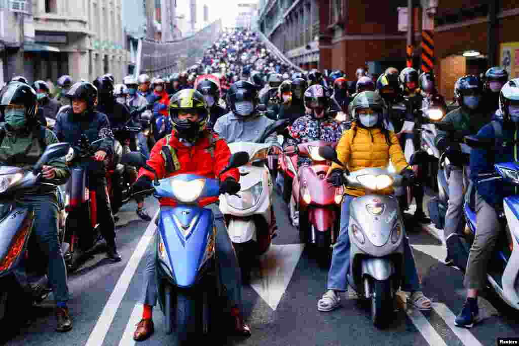 People on motorbikes wait at a traffic light during morning rush hour in Taipei, Taiwan.