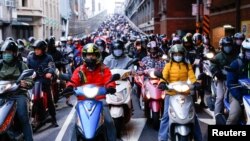 People on motorbikes wait at a traffic light during morning rush hour in Taipei, Taiwan.