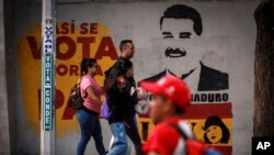 Pedestrians walk past a campaign mural featuring President Nicolas Maduro, in Caracas, Venezuela, Aug. 2, 2024.