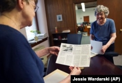 Benedictine sisters Rose Marie Stallbaumer, left, and Barbara McCracken, right, search through archives of corporate resolutions and newspaper clippings at Mount St. Scholastica Monastery in Atchison, Kansas, Tuesday, July 16, 2024. (AP Photo/Jessie Wardarski)