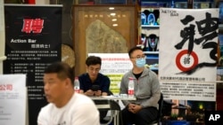 (FILE) Recruiters sit at a booth at a job fair in a shopping center in Beijing, China, June 9, 2023.