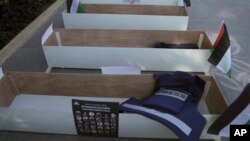 FILE - Mock coffins with photos of Palestinian journalists killed during the current war in Gaza are prepared by fellow journalists for a symbolic funeral march toward a United Nations office in the West Bank city of Ramallah, Nov. 7, 2023.