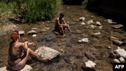 A couple cool off in the Guadiaro river at "La Cueva del Gato" near Benaojan, in southern Spain on July 15, 2023.