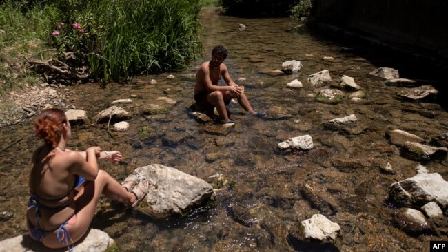 A couple cool off in the Guadiaro river at "La Cueva del Gato" near Benaojan, in southern Spain on July 15, 2023.