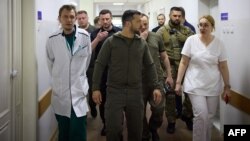 Ukraine's President Volodymyr Zelensky listening to a doctor during his visit to local residents evacuated from a flooded area in Kherson, June 8, 2023. (AFP photo / Handout /Ukrainian Presidential Press Service) 