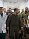 Ukraine's President Volodymyr Zelensky listening to a doctor during his visit to local residents evacuated from a flooded area in Kherson, June 8, 2023. (AFP photo / Handout /Ukrainian Presidential Press Service) 