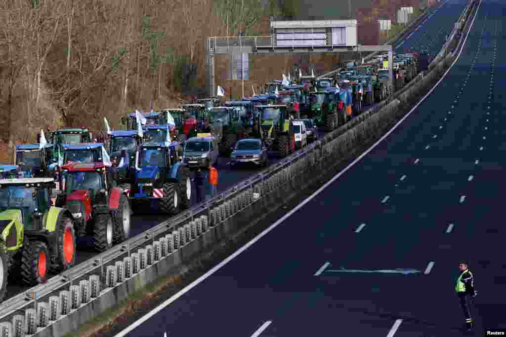 French farmers use their tractors to block the A1 highway near a highway toll station as they protest over price pressures, taxes and green regulation, near Paris, France.