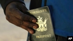 FILE - A man puts an expired passport in his pocket while waiting in a queue to submit an application for a new passport at the main office in Harare, June 14, 2019. 