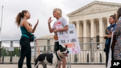 FILE - Lilo Blank, of Philadelphia (L), who supports abortion rights, and Lisa Verdonik, of Arlington, Va., who is anti-abortion, talk about their opposing views on abortion rights, May 13, 2022, outside the Supreme Court in Washington.