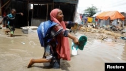 A schoolgirl wades through floodwaters outside makeshift shelters following heavy rains at the Al Hidaya camp for the internally displaced people on the outskirts of Mogadishu, Somalia, Nov. 6, 2023.