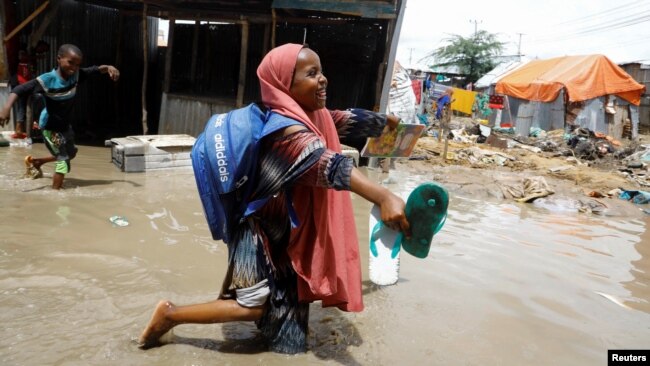 A schoolgirl wades through floodwaters outside makeshift shelters following heavy rains at the Al Hidaya camp for the internally displaced people on the outskirts of Mogadishu, Somalia, Nov. 6, 2023.