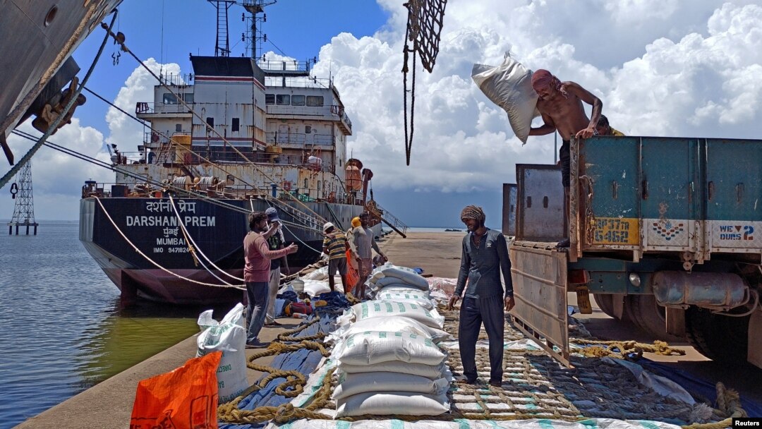 Para buruh membongkar karung beras dari truk pemasok di pelabuhan beras utama India di Kakinada Anchorage di negara bagian Andhra Pradesh (foto: dok). India berlakukan larangan ekspor beras untuk menekan laju inflasi yang tinggi. 