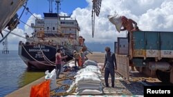 Para buruh membongkar karung beras dari truk pemasok di pelabuhan beras utama India di Kakinada Anchorage di negara bagian Andhra Pradesh (foto: dok). India berlakukan larangan ekspor beras untuk menekan laju inflasi yang tinggi. 