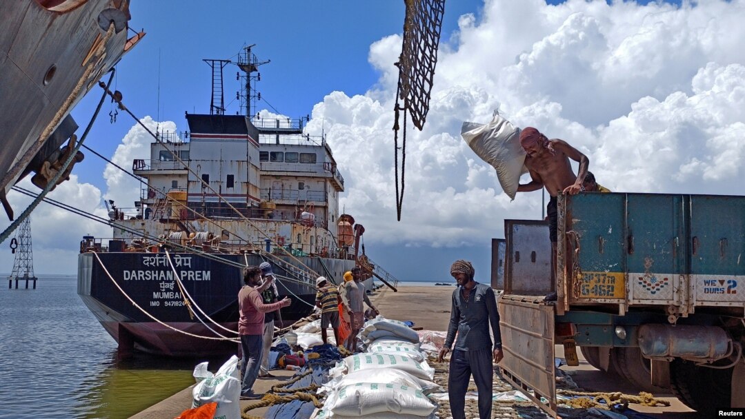 Sejumlah pekerja menurunkan beras dari sebuah truk di pelabuhan utama ekspor beras India di Kakinada Anchorage, negara bagian Andhra Pradesh, India, 2 September 2021. (Foto: Rajendra Jadhav/Reuters)
