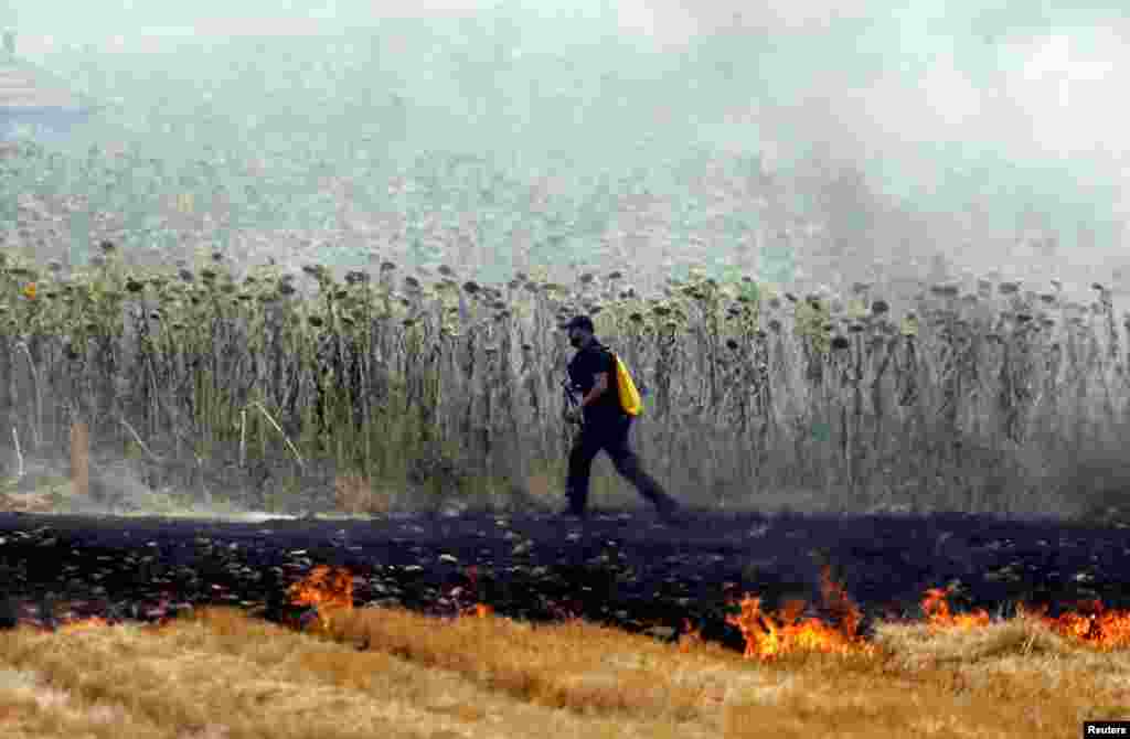 A firefighter walks by a wildfire in a field near Stip, North Macedonia.