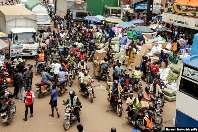 Drivers of motorcycle taxis, known locally as boda-bodas, ride with passengers on a street of Kampala, Uganda, on July 18, 2024. (AP Photo/Hajarah Nalwadda )