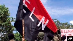 ARCHIVO - En esta fotografía de archivo del 12 de octubre de 1998, miembros del Ejército de Liberación Nacional (ELN) izan su bandera en San Francisco, una región montañosa del norte de Colombia.