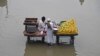 Penjual buah menunggu pembeli di tengah jalan yang terendam banjir di kota Karachi pada 24 Juli 2023. (Foto: AFP)