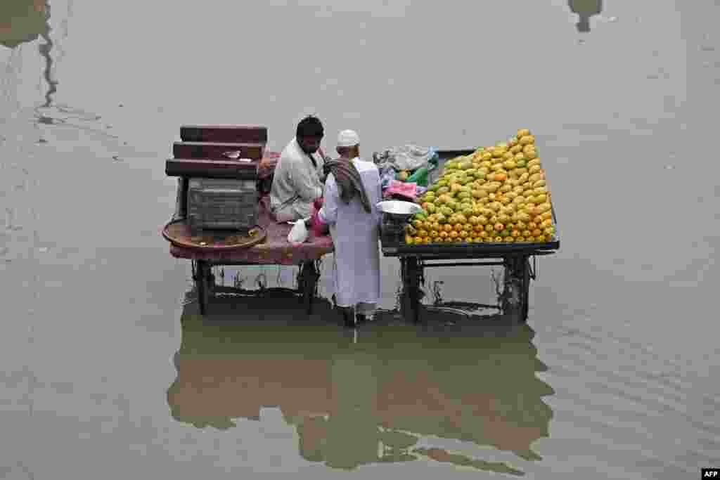 Продавачите на овошје чекаат муштерии на поплавена улица во Карачи, Пакистан.