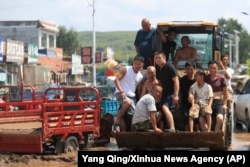 In this photo released by Xinhua News Agency, residents are evacuated by a bulldozer from floodwaters in Heishanke Township, the city of Huludao in Liaoning province, Aug. 21, 2024.