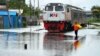 Seorang petugas memandu kereta api melewati jalur yang tergenang banjir di Semarang, Jawa Tengah, 5 Februari 2021. (Foto: Daffa Ramya Kanzuddin/AFP)