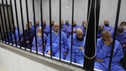 Para tersangka militan kelompok Negara Islam (IS) duduk di bilik terdakwa selama persidangan di kota Misrata, Libya barat laut pada 29 Mei 2023. 