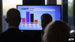 People look at a screen with the first exit polls results for Thuringia's state elections, at the State Parliament in Erfurt, eastern Germany, Sept. 1, 2024. 