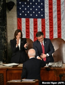 Presiden AS Joe Biden berjabat tangan dengan Ketua DPR Mike Johnson (R-LA) saat Wakil Presiden Kamala Harris menyaksikan pidato kenegaraan di DPR AS Capitol di Washington, DC, 7 Maret 2024. (Foto: Mandel Ngan/AFP)