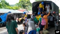 Tentara membantu warga turun dari truk militer di pusat evakuasi di kota Santo Domingo, provinsi Albay, Filipina timur laut, Selasa, 13 Juni 2023. (AP/Aaron Favila)