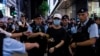 Seorang anggota masyarakat dikawal oleh polisi setelah menyorotkan cahaya dari smartphone, di dekat Taman Victoria, yang menjadi lokasi peringatan 34 tahun penumpasan Lapangan Tiananmen China di Hong Kong, Minggu, 4 Juni 2023 (Foto AP/Louise Delmotte)