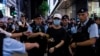 A member of the public is escorted by police after shining the light from a smartphone, near Victoria Park, the city's venue for the annual 1989 Tiananmen massacre vigil, on the 34th anniversary of China's Tiananmen Square crackdown in Hong Kong, June 4, 2023.