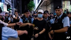 Seorang anggota masyarakat dikawal oleh polisi setelah menyorotkan cahaya dari smartphone, di dekat Taman Victoria, yang menjadi lokasi peringatan 34 tahun penumpasan Lapangan Tiananmen China di Hong Kong, Minggu, 4 Juni 2023 (Foto AP/Louise Delmotte)