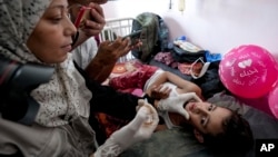 A health worker administers a polio vaccine to a child at a hospital in Khan Younis, Aug. 31, 2024. 