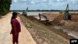 FILE - This photo taken July 9, 2024, shows villager Sok Rom looking at excavators being used on the construction of the Funan Techo Canal along the Prek Takeo channel in Kandal province. 