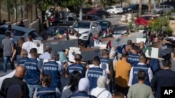 FILE - Palestinian journalists carry mock coffins of colleagues killed during the current Israel-Hamas war, during a symbolic funeral procession toward a United Nations office in the West Bank city of Ramallah, Nov. 7, 2023.