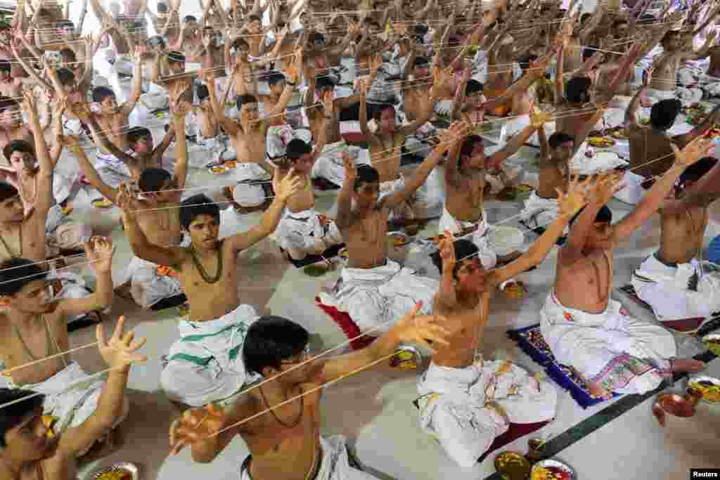 Para remaja pria Hindu Brahmana mengambil bagian dalam upacara pergantian &quot;janeu&quot; (benang suci), yang juga disebut &quot;yagnopavit&quot; di luar kuil pada perayaan festival Raksha Bandhan di Ahmedabad, India.