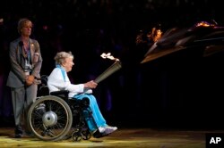 FILE - Margaret Maughan, Britain's first Paralympic gold medalist, lights the Paralympic flame during the Opening Ceremony for the 2012 Paralympics in London, Aug. 29, 2012.