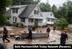 Emergency personnel maneuver a boat to rescue residents of flooded homes following flash flooding from torrential rain throughout the Lower Hudson Valley, in Stony Point, New York, July 9, 2023.