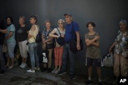 Residents take cover next to a wall as explosions are heard nearby during a Russian attack in Kherson, Ukraine, June 16, 2023.