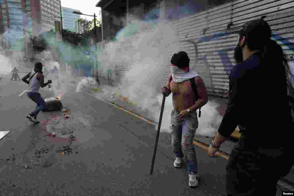 Manifestantes corren para protegerse de los gases lacrimógenos en Caracas, el 29 de julio de 2024.